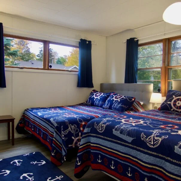 The third bedroom in Cabin 1 at Sunset Shore Mille Lacs features two queen beds, offering a spacious and comfortable retreat for guests.