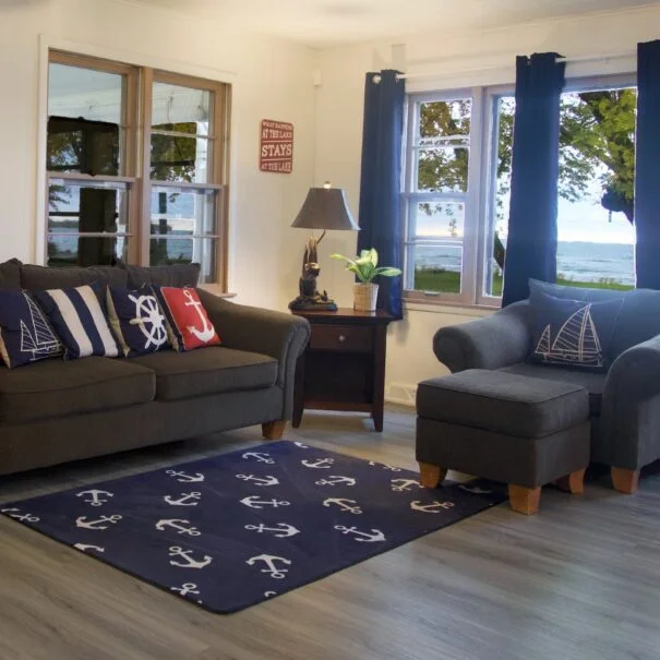 A cozy family room in Cabin 1 at Sunset Shore Mille Lacs, with a couch, chair, and stunning views of the lake.