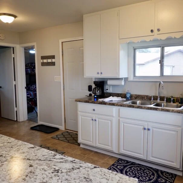 A kitchen with white cabinets, countertops, and appliances.
