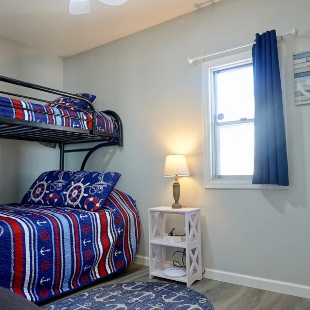 A bedroom with a bunk bed, blue curtains, and nautical-themed decor.